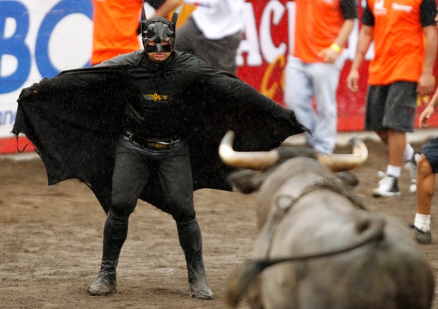 Image: A man wearing a Batman costume gestures towards a bull in an improvised bullring during the annual bullfight festival in Zapote, near San Jose