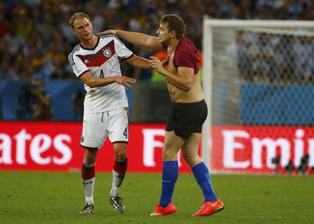 A spectator runs onto the pitch to talk to Germany's Benedikt Hoewedes during the 2014 World Cup final between Germany and Argentina at the Maracana stadium