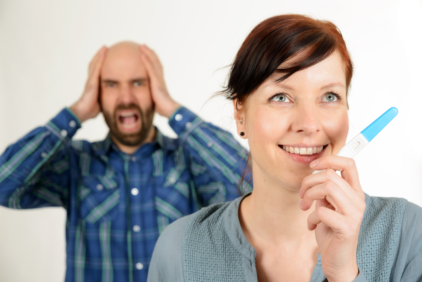 Lachende Frau und schreiender Mann mit Schwangerschaftstest