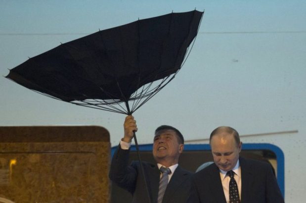 A security personnel struggles with an umbrella as Russia's President Putin walks out of a plane upon arriving at the airport ahead of the fourth summit of the CICA held in Shanghai