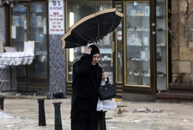 Pedestrian holds an umbrella as she walks against the wind in Jerusalem