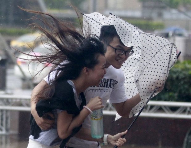 People hold onto their umbrella while walking against strong winds caused by Typhoon Dujuan in Taipei