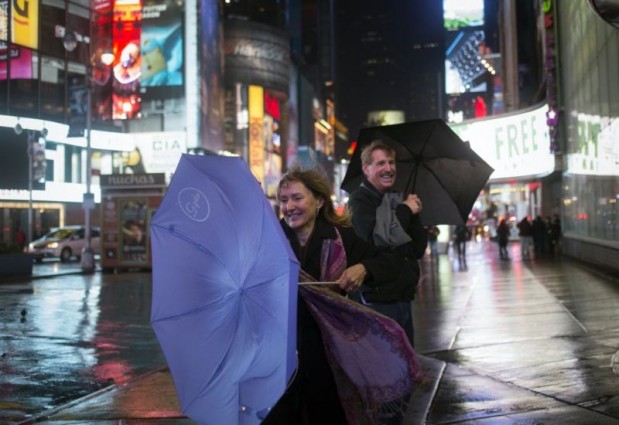 A visitor from New Mexico tries to hold onto her umbrella while taking pictures in Times Square in New York