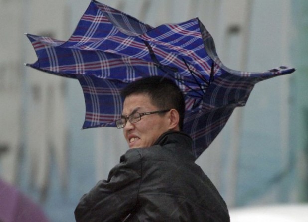 A man's umbrella is blown by wind during a heavy rain in Yantai