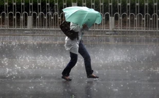 A woman struggles to hold an umbrella as she walks through a storm in Beijing