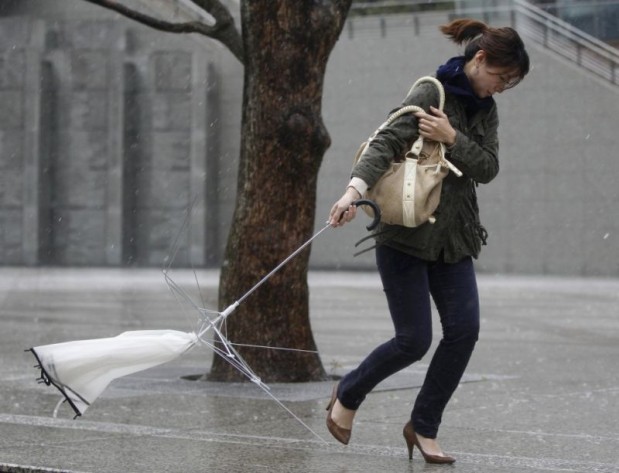 A woman holds a broken umbrella as she walks in strong wind and rain in Tokyo
