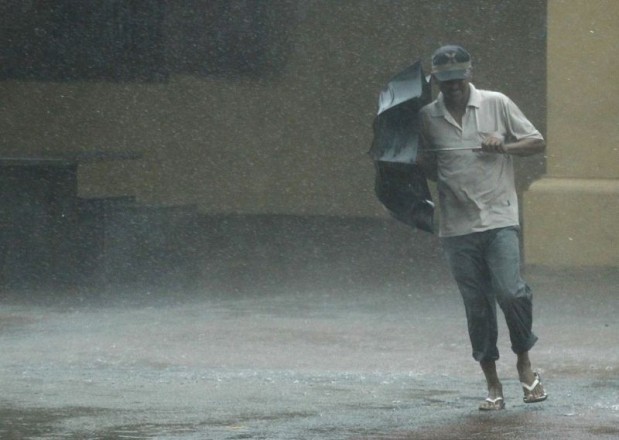 A man struggles with an umbrella as he runs in the rain in Colombo