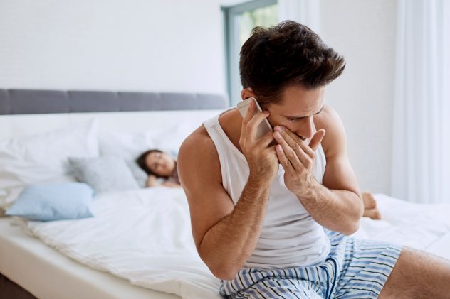 Handsome young man cheating on girlfriend talking with lover while she is sleeping in the background