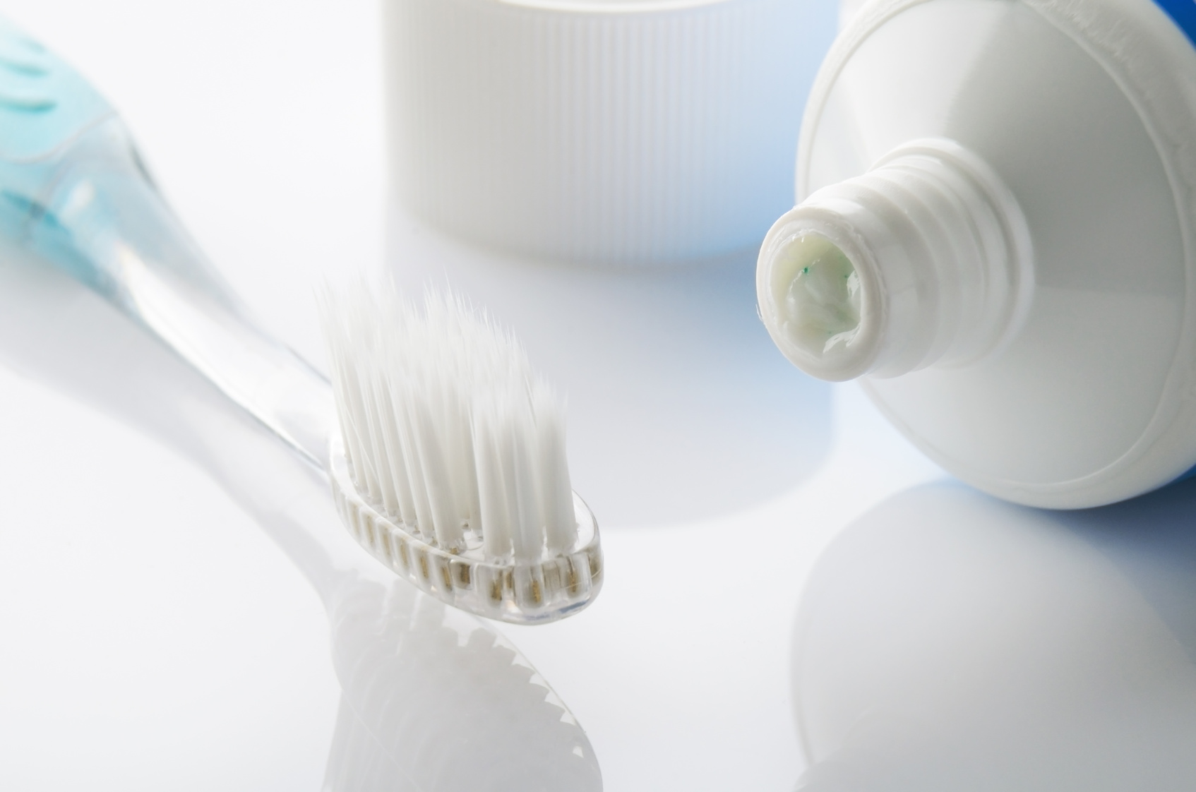 turquoise toothbrush and toothpaste on white table